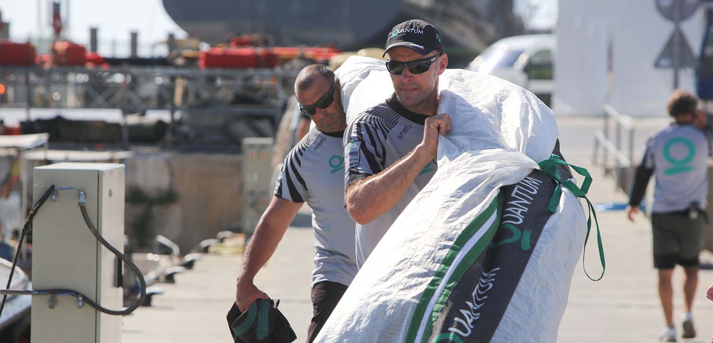 Equipe de vela transportando equipamento em uma marina